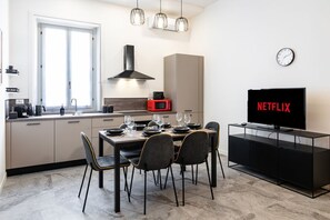Eine moderne Küche mit Essbereich, einem Fernseher und einer Uhr an der Wand.
