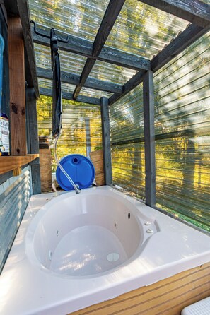 Ein Wellnessbereich mit Whirlpool, Holzbalken und Blick durch ein Fenster.