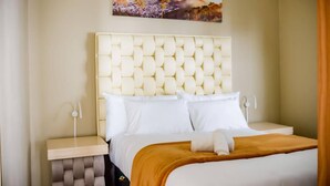A hotel room with a tufted headboard, white bedding, a brown throw blanket, and a painting of a mountain landscape. - Room-makays Guests House Kimberley (Kimberley)