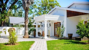 A modern house with a white exterior, a covered porch, and a paved pathway leading to the entrance. - Room-makays Guests House Kimberley (Kimberley)