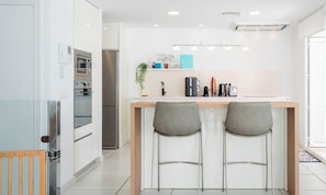 Eine moderne Küche mit einer zentralen Kochinsel, Barhocker und einem Kühlschrank.
