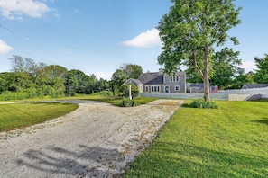 A residential property with a gravel driveway, a lawn, and a large house with a porch. - East Dennis Gem! Walk to Beach! Sleeps 10! (Dennis)