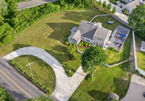 A large house with a driveway, a lawn, and a small deck. - East Dennis Gem! Walk to Beach! Sleeps 10! (Dennis)