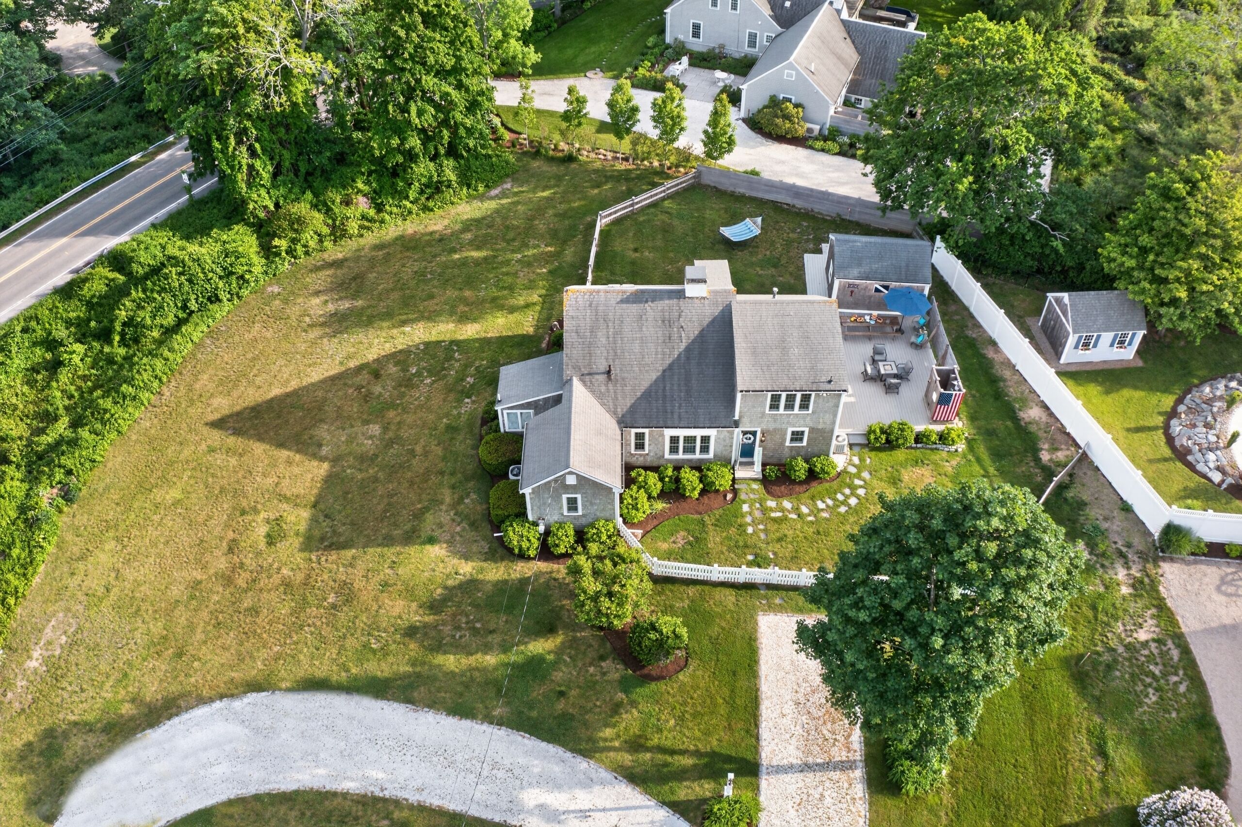 A residential property with a large lawn, a fenced yard, and a house with a garage.