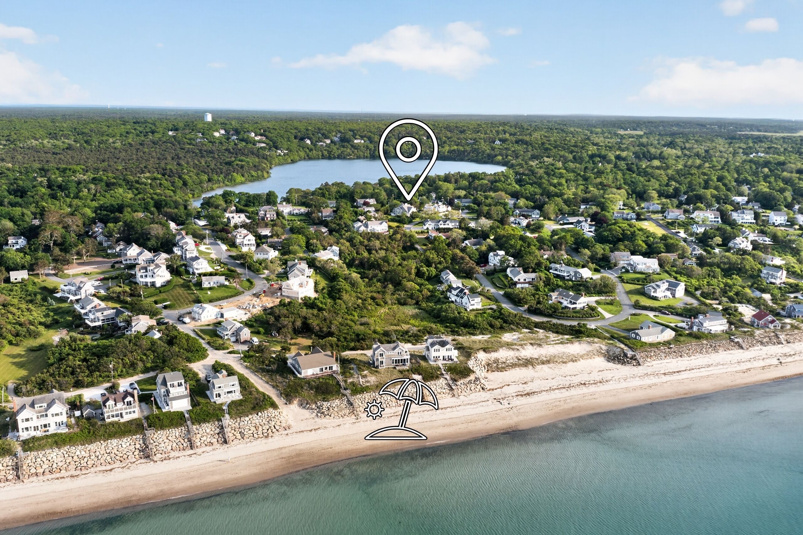 An aerial view of a coastal residential area with houses, a beach, and a lake.