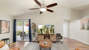 Una sala de estar con ventilador de techo, televisor, mesa de centro y sofá.