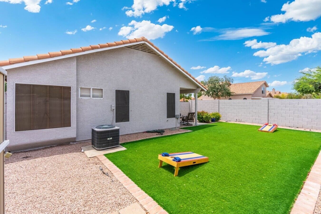 A residential property with a well-maintained lawn, a patio area, and a brick wall.