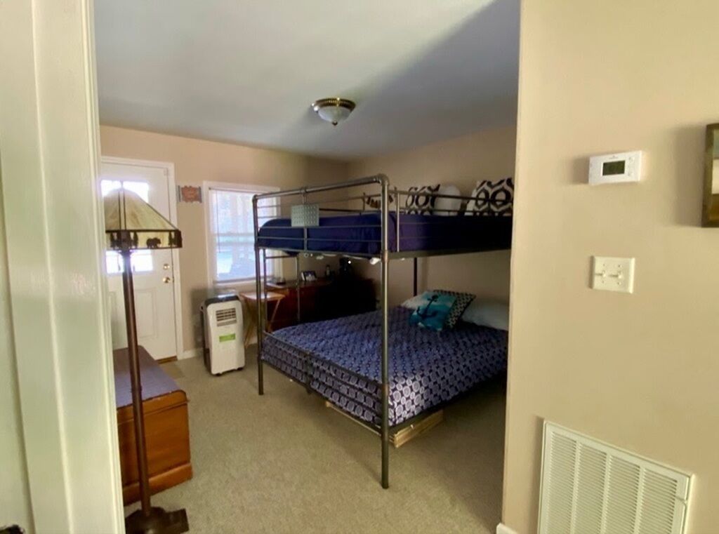 Une chambre avec un lit superposé, un radiateur, un bureau et une fenêtre.