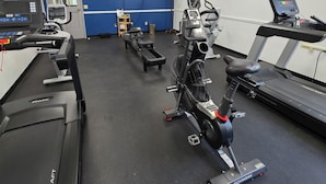 A gym with treadmills, stationary bikes, and a wall-mounted TV.