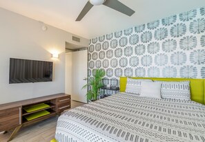 A bedroom with a bed, a desk, a plant, and a wall-mounted TV. - Beautiful Mid Century Modern 2/2 with resort style backyard in Sun City West (Sun City West)