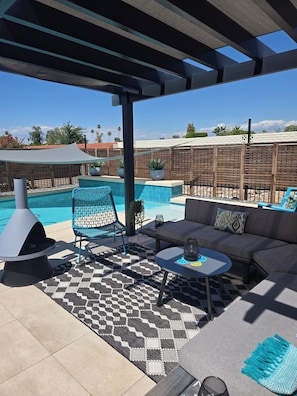 Ein überdachter Außenbereich mit Pool, Grill und Blick auf die umliegende Landschaft.