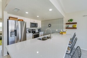 A modern kitchen with stainless steel appliances, a central island, and a patterned backsplash. - Beautiful Mid Century Modern 2/2 with resort style backyard in Sun City West (Sun City West)