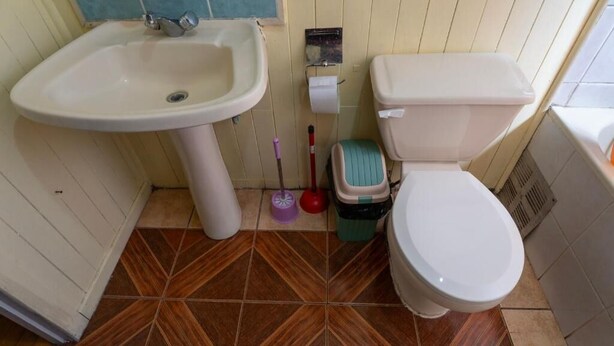A bathroom with a sink, toilet, and a mop. - hostal refugio nomada (Puerto Montt)