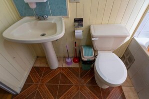A bathroom with a sink, toilet, and a mop. - hostal refugio nomada (Puerto Montt)