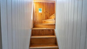 A wooden staircase leading to a room with a wooden wall and a green emergency exit sign. - hostal refugio nomada (Puerto Montt)