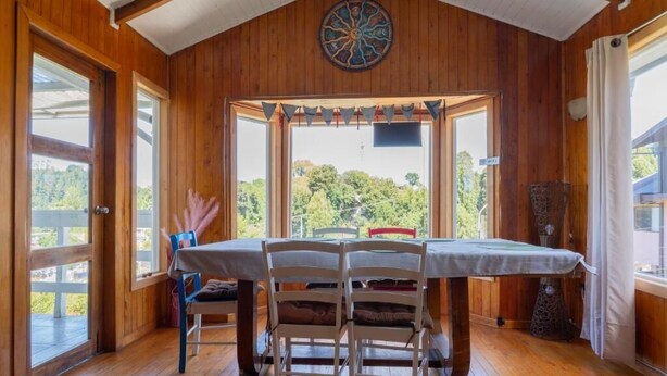 A wooden interior with a dining table and chairs, large windows, and a decorative ceiling piece. - hostal refugio nomada (Puerto Montt)