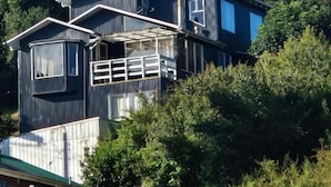 A two-story building with a balcony, a chimney, and a satellite dish. - hostal refugio nomada (Puerto Montt)