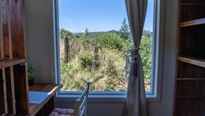 A room with a large window, a wooden desk, a chair, and a shelf. - hostal refugio nomada (Puerto Montt)