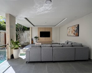 Ein modernes Wohnzimmer mit einem grauen Ecksofa, einem Flachbildfernseher und einem großen abstrakten Gemälde.