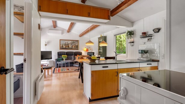 Une cuisine moderne avec des meubles en bois, un îlot central et un coin repas comprenant un canapé et une table.