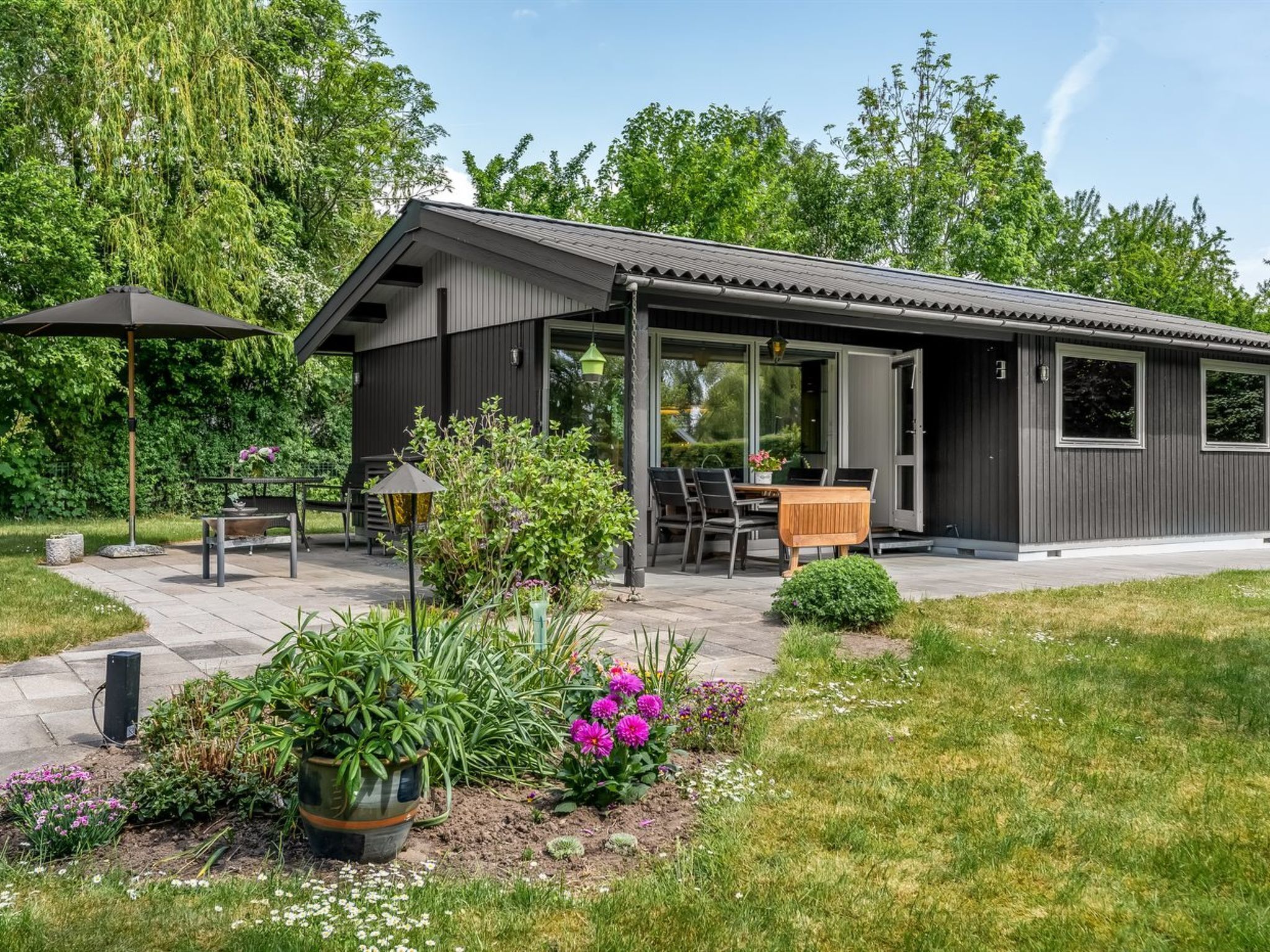 Une maison moderne dotée d’un patio, d’un espace salon extérieur et d’un jardin.