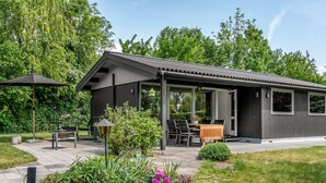 Une maison moderne dotée d’un patio, d’un espace salon extérieur et d’un jardin.
