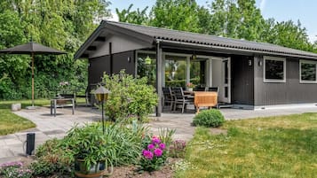 Une maison moderne dotée d’un patio, d’un espace salon extérieur et d’un jardin.
