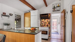 Une cuisine moderne dotée d’un îlot central, de meubles blancs et d’un plafond en bois.