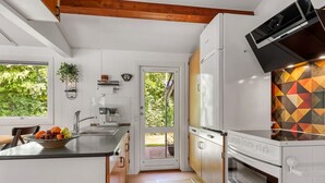 Une cuisine moderne dotée d’un four encastré, d’une machine à café et d’une grande fenêtre.