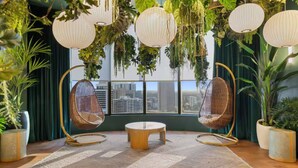A room with two wicker chairs, a round table, and a view of a cityscape through large windows. - Luxury 2BR Sky Retreat Best Miami Bay Views (Miami)