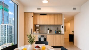 A modern hotel room with a dining area, kitchenette, and a view of a cityscape. - Luxury 2BR Sky Retreat Best Miami Bay Views (Miami)