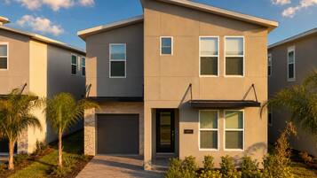 A modern two-story residential building with a brick entrance, a garage, and a well-maintained garden.