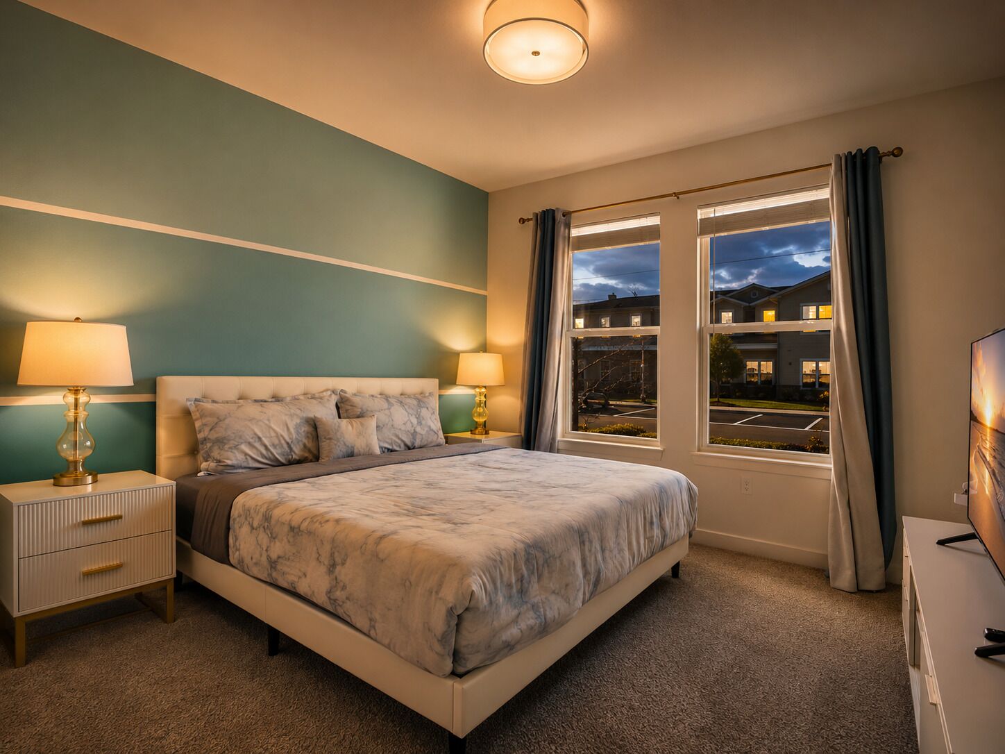A bedroom with a bed, two bedside tables, a nightstand, a dresser, and a window with curtains.