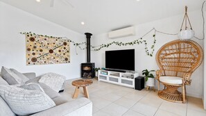 Ein modernes Wohnzimmer mit Sofa, Fernseher, Kamin und Wandkunst.