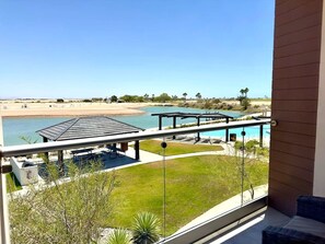 Un balcon avec vue sur une piscine, une plage et un ciel dégagé.