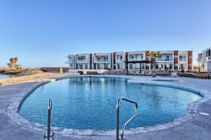 Une piscine avec un bĂątiment moderne en arriĂšre-plan.