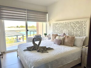 Habitación de hotel con una cama grande, un cabecero decorativo, vistas al exterior y un balcón.