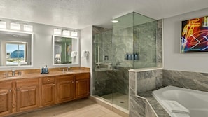 A modern bathroom with a glass-enclosed shower, a large mirror, and a bathtub.
