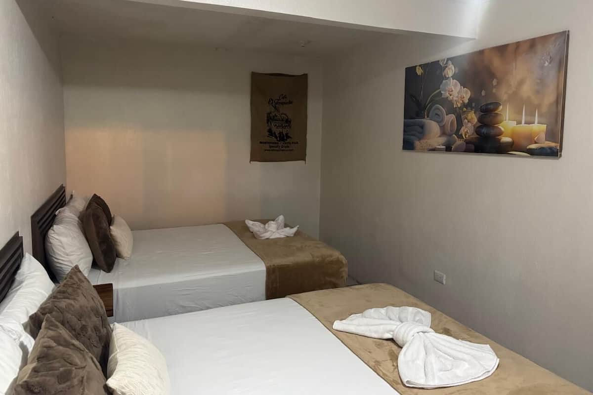 Habitación de hotel con dos camas, un cuadro y un perchero.