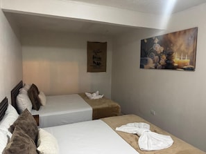 A hotel room with two beds, a painting, and a towel rack.