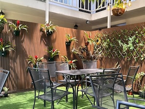 A patio with a table and chairs, surrounded by potted plants and a wooden fence.