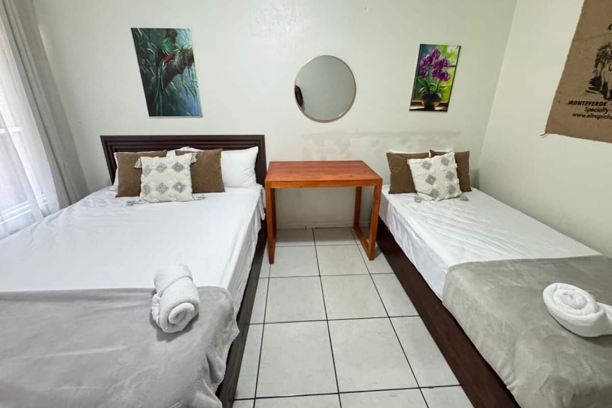 Habitación de hotel con dos camas, un espejo redondo y dos cuadros colgados en la pared.