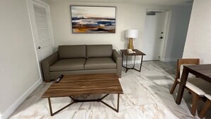 Un salon avec un canapé, une table basse, une lampe et un tableau au mur.