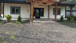 Ein Haus mit überdachter Veranda, weißen Außenwänden und schwarzen Fensterrahmen.