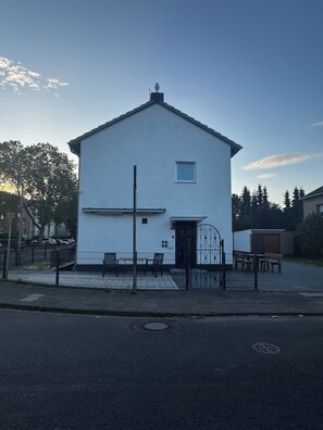 Un edificio blanco con una pequeña ventana, una puerta y una reja de metal.