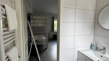 Un bagno rivestito di piastrelle bianche, con lavandino e specchio.