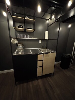Una kitchenette compacta con pileta, alacenas y un bote de basura.