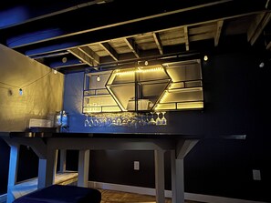 A bar area with a geometric light fixture, a counter, and hanging glasses. - Sterling fountain-City of fountains (Kansas City)