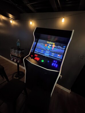 Una consola de videojuegos con pantalla mostrando un juego, rodeada de luces fijadas a la pared.