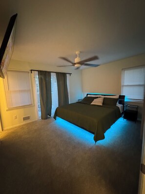Un dormitorio con una cama, ventilador de techo y ventana con persianas.